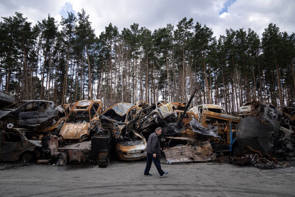 A man walks past a storage place for burned armed vehicles and cars, in the outskirts of Kyiv, Ukraine