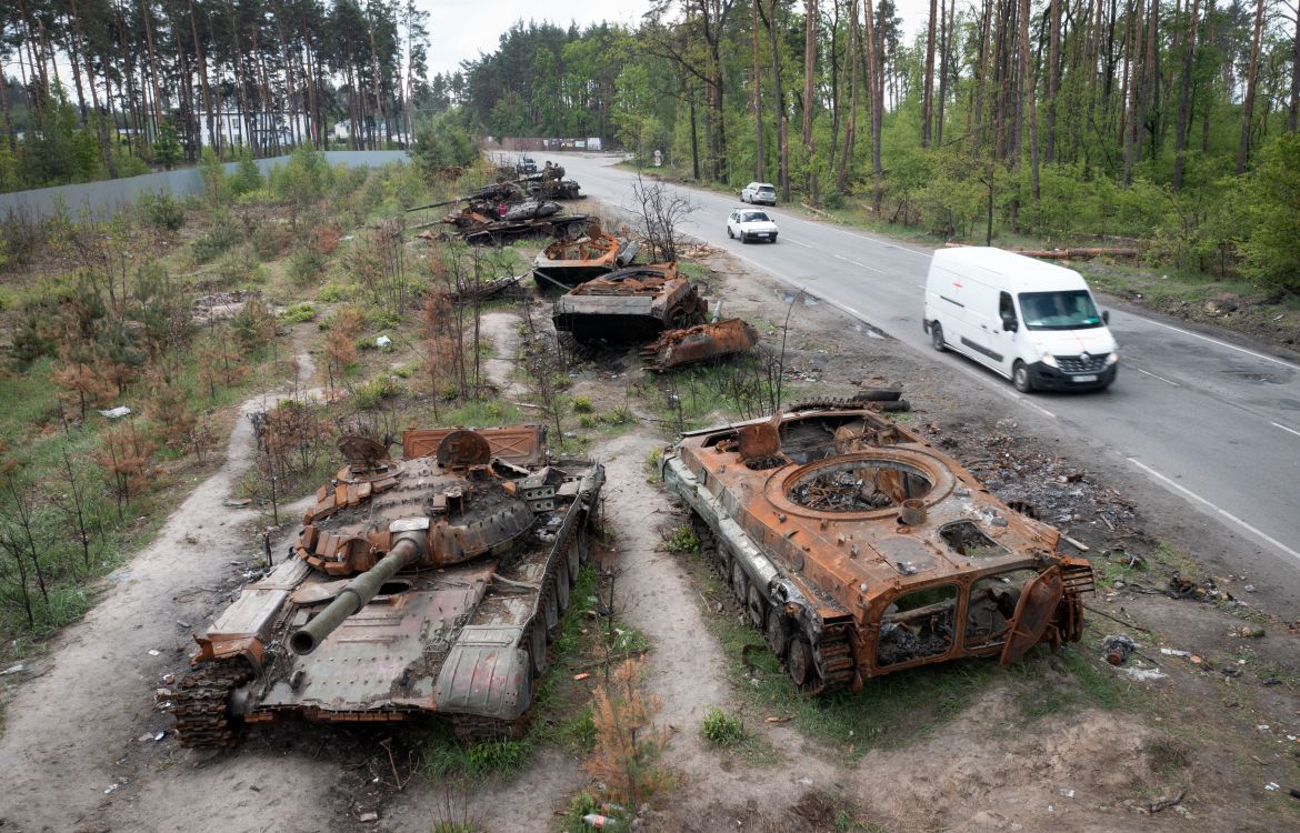 Cars pass by destroyed Russian tanks in a recent battle against Ukrainians in the village of Dmytrivka, close to Kyiv, Ukraine