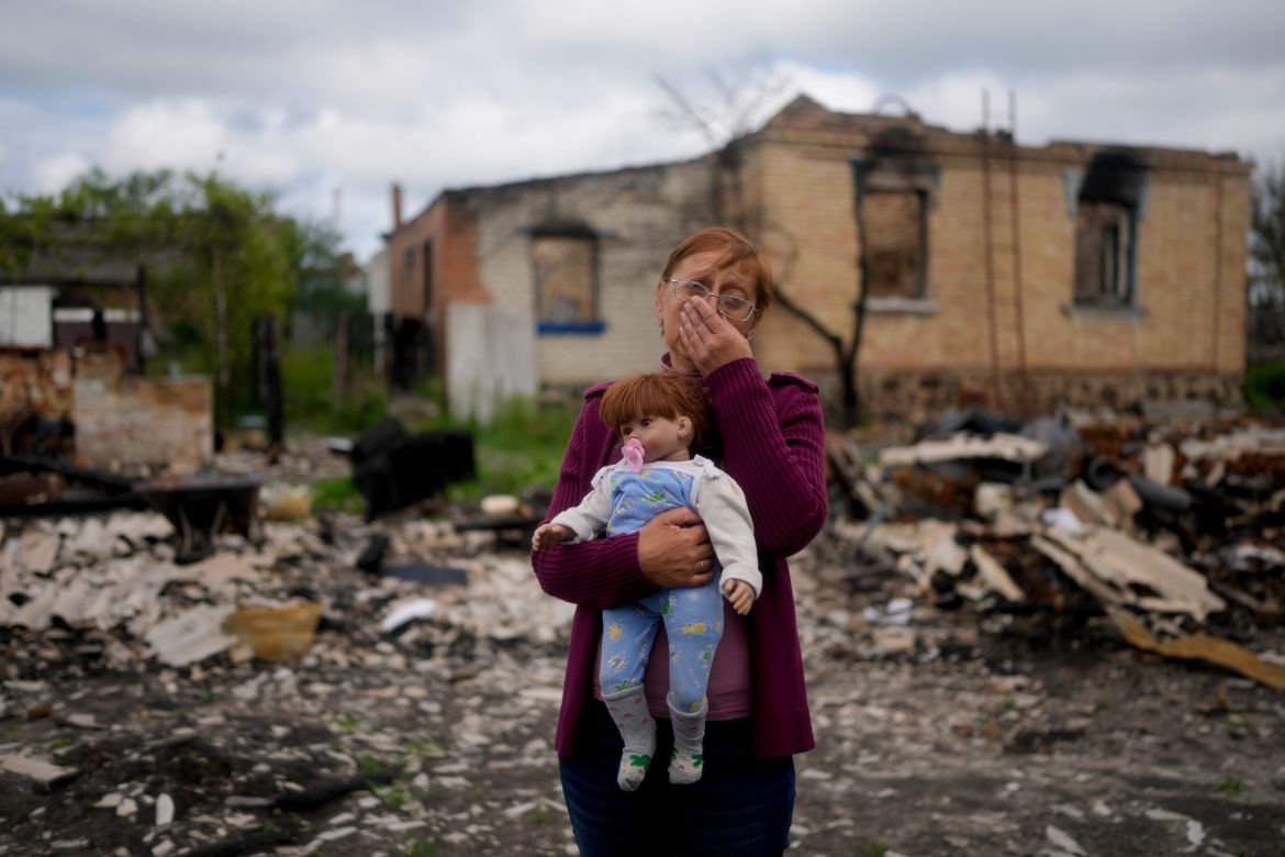 Nila Zelinska holds a doll belonging to her granddaughter, she was able to find in her destroyed house in Potashnya outskirts Kyiv, Ukraine