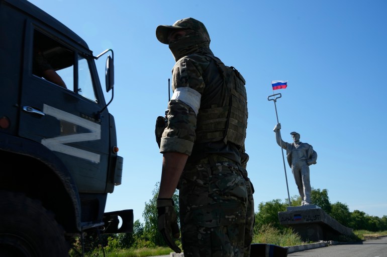A Russian soldier is seen standing next to a military truck marked with the letter Z, which has become a symbol of Russia's armed forces