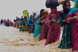 Rescue workers help residents evacuate from a flooded area caused by heavy rains, in Balochistan&#39;s Lasbela district [File: Hamdan Khan/AP]