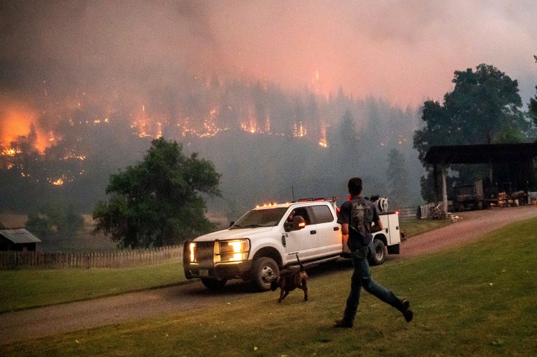 A man runs to a truck as a wildfire called the McKinney fire burns in Klamath National Forest, California.