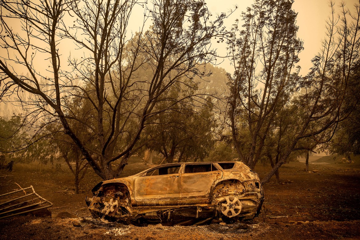 A scorched vehicle rests sits next to a driveway as the McKinney Fire burns in Klamath National Forest