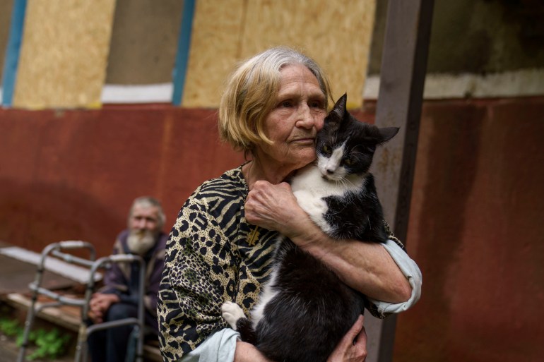 Raya Ilyevich, 86, holds her cat, Murchik, outside her damaged apartment from Russian shelling in Kramatorsk, Donetsk region, eastern Ukraine, Tuesday, Aug. 2, 2022. While the government's order to evacuate has convinced some of those left in the Donetsk region to flee, others like Ilyevich are resistant saying they have nowhere else to go. (AP Photo/David Goldman)