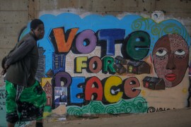 A woman walks past an electoral mural calling for peace, in the low-income Kibera neighbourhood of Nairobi, Kenya on Aug 4, 2022. Kenya is due to hold elections on Tuesday, Aug. 9 [Brian Inganga/AP]