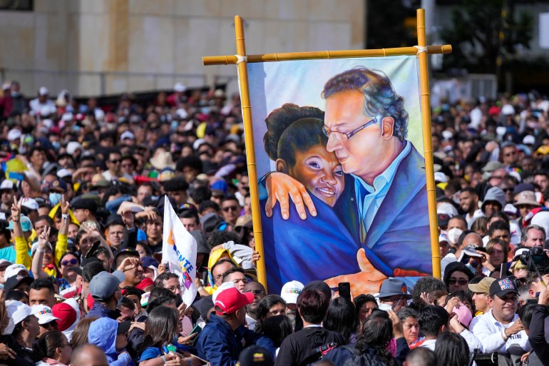 Apoiadores do presidente da Colômbia, Gustavo Petro, exibem uma pintura dele com a vice-presidente Francia Marquez durante sua cerimônia de posse na praça Bolívar, em Bogotá, Colômbia.
