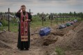 A priest prays for unidentified civilians killed by Russian troops during Russian occupation in Bucha, on the outskirts of Kyiv, Ukraine, Thursday