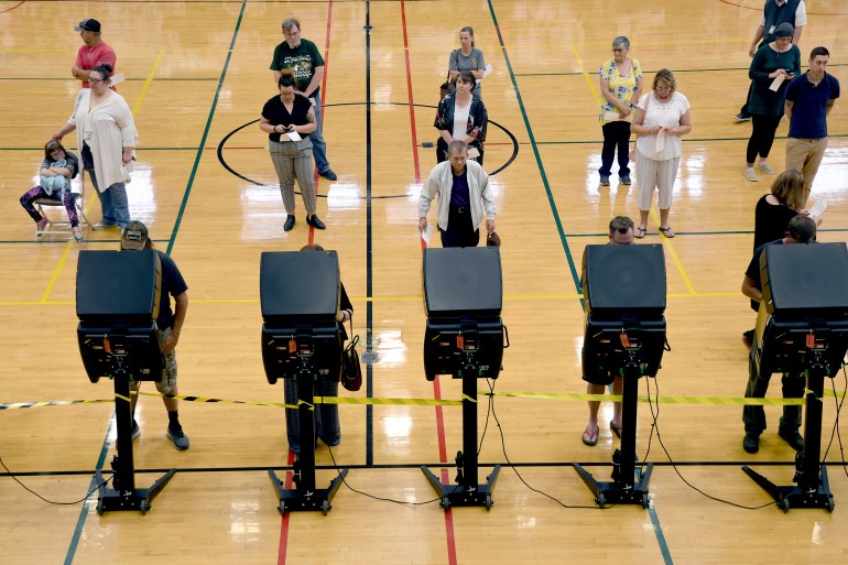Voters queue up in front of ballot boxes laid out in a sports hall waiting to vote