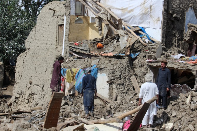 People clear their damaged houses after severe flooding in Khushi district of Logar province.