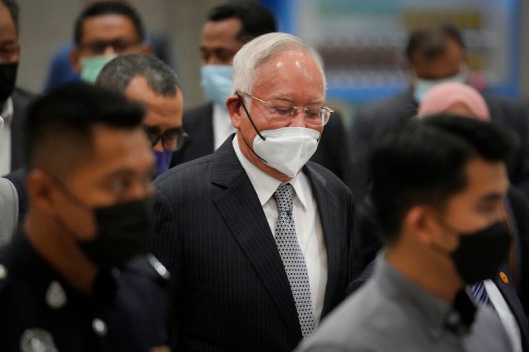 Former Malaysian Prime Minister Najib Razak, center, wearing a face mask, waves as he arrives at Court of Appeal in Putrajaya, Malaysia, on Tuesday, August 23, 2022. Najib was sentenced to 12 years in jail by a high court in July 2020, after being found guilty of abuse of power, criminal breach of trust and money laundering for illegally receiving 42 million ringgit ($9.4 million) from SRC International, a former unit of 1MDB [Vincent Thian/AP]
