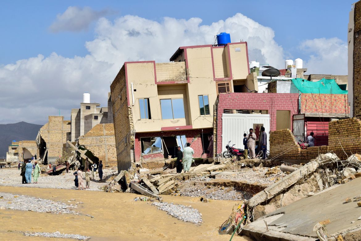People stand in their partially damage homes