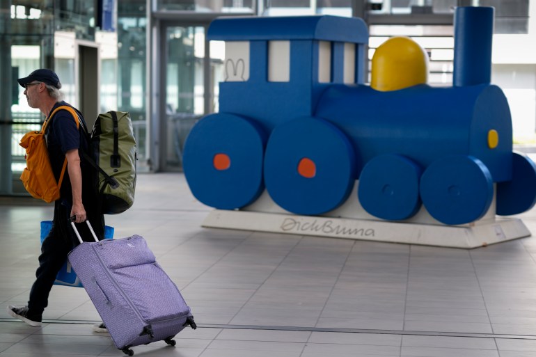 A stranded traveller passes an artwork of a blue train by Miffy creator Dick Bruna, at Utrecht central station as train services came to a near standstill