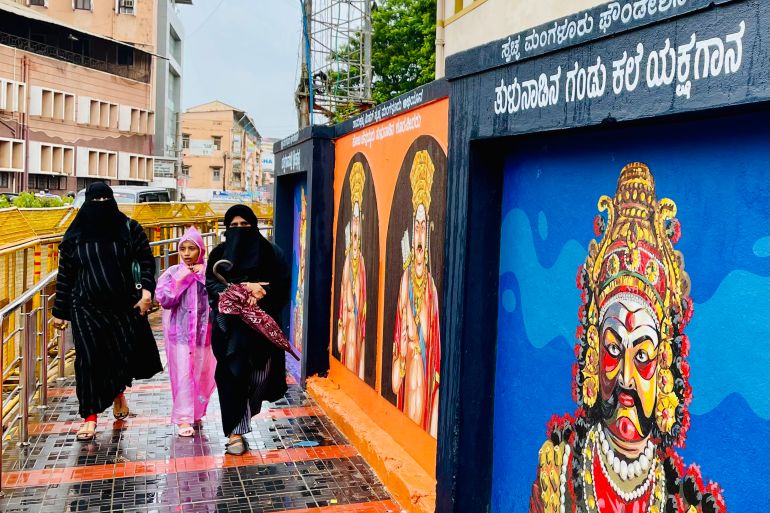 Burqa-clad women walk past graffiti of Hindu gods, which can be seen across the walls of the city.