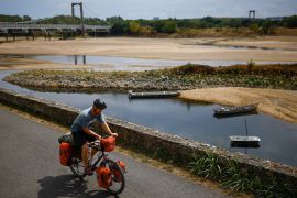 A cyclist rides near a branch of the Loire River as historical drought hits France