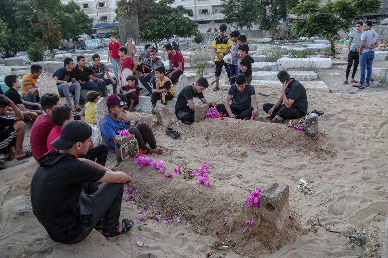 Friends of Hamed Najm sit near their graves in the same cemetery where they were killed