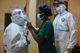Head nurse Josephine Alabi helps her colleagues put on the PPE