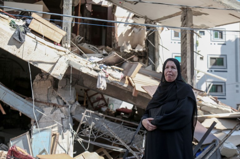 Khadra Khalifa inspects what remains of her home after it was destroyed by Israeli forces [Abdelhakim Abu Riash/Al Jazeera]