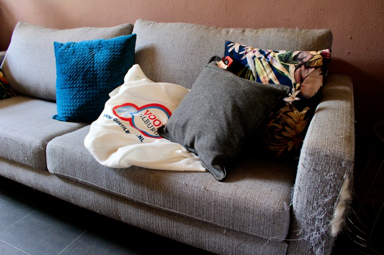 A photo of a sofa with pillows and a tote bag on it.