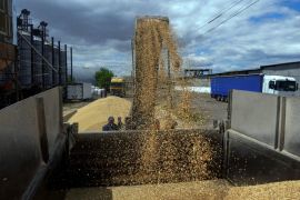 A worker loads a truck with grain at a terminal during barley harvesting in Odesa