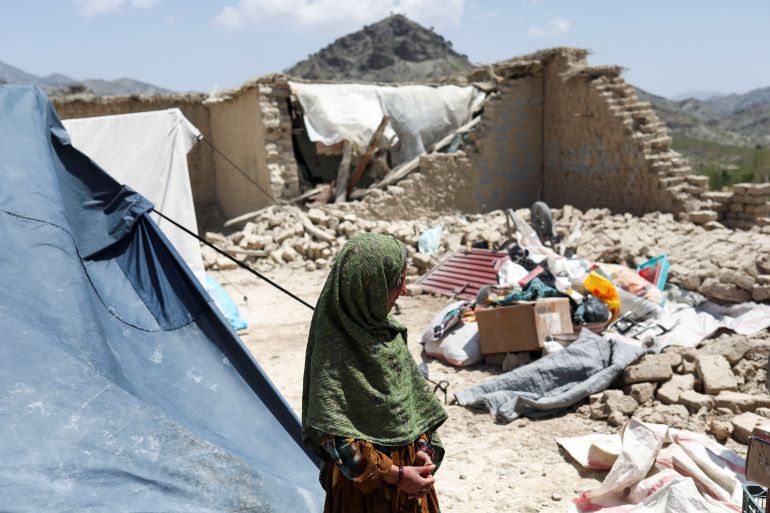 An Afghan girl stands near what was once her house, destroyed by an earthquake in June, in Afghanistan's Paktika province.