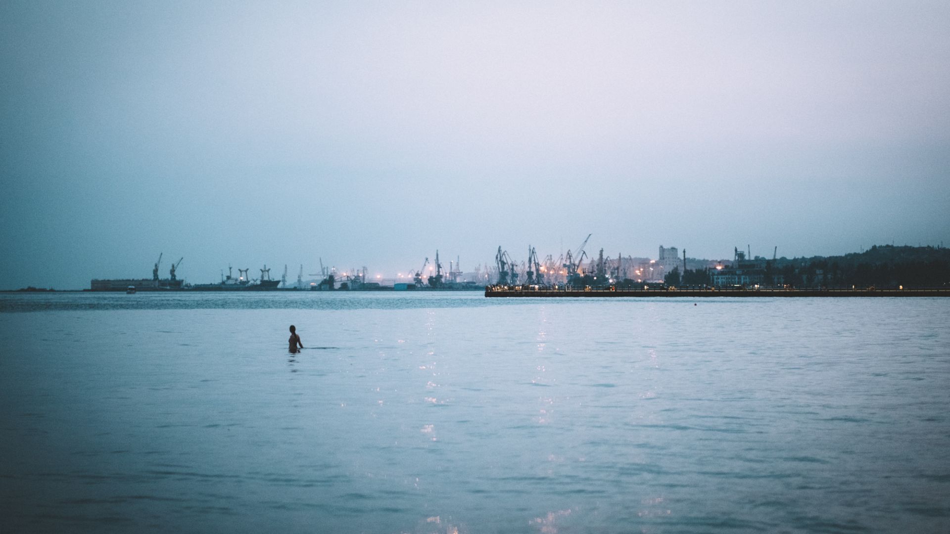 A photo of a large body of water with a person swimming in it.