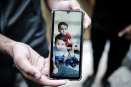 Umm Mohammad al-Nairab, 60, weeps as she shows an image of her grandchildren who were killed in Israeli raids [Hosam Salem/Al Jazeera]