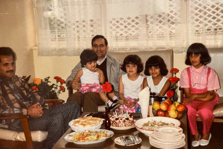 A photo of two men posing with their four daughters/nieces with a table laden with cakes and food in front of them