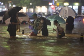 People wade though a flooded road in the South Korean capital, Seoul. [Yonhap/EPA]