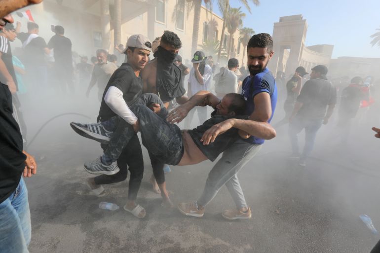 Supporters of Iraqi Shiite cleric Muqtada al-Sadr help injured protesters during clashes with anti-riot forces near the office of prime minister