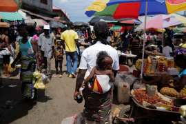 A woman carries her daughter as she walks at Gobachop market in Monrovia, Liberia