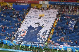 Japan fans hold a giant banner of popular Japanese manga series star Captain Tsubasa before the Russia 2018 World Cup knockout match against Belgium [Jewel Samad/AFP]