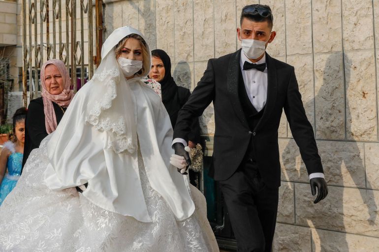 Newly-wed Palestinians Yazen Abu Ramooz (R) and Iman Ghaith, both wearing protective masks during the COVID-19 coronavirus pandemic, walk in the neighbourhood of Beit Hanina in Israeli annexed East Jerusalem, on April 17, 2020. (Photo by