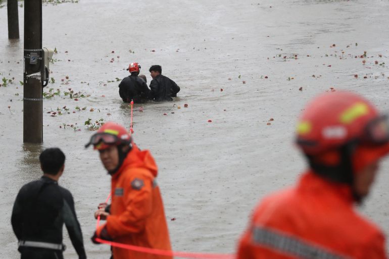 Rescue workers in orange suits rescue a man from a flooded park in Ulsan in South Korea.