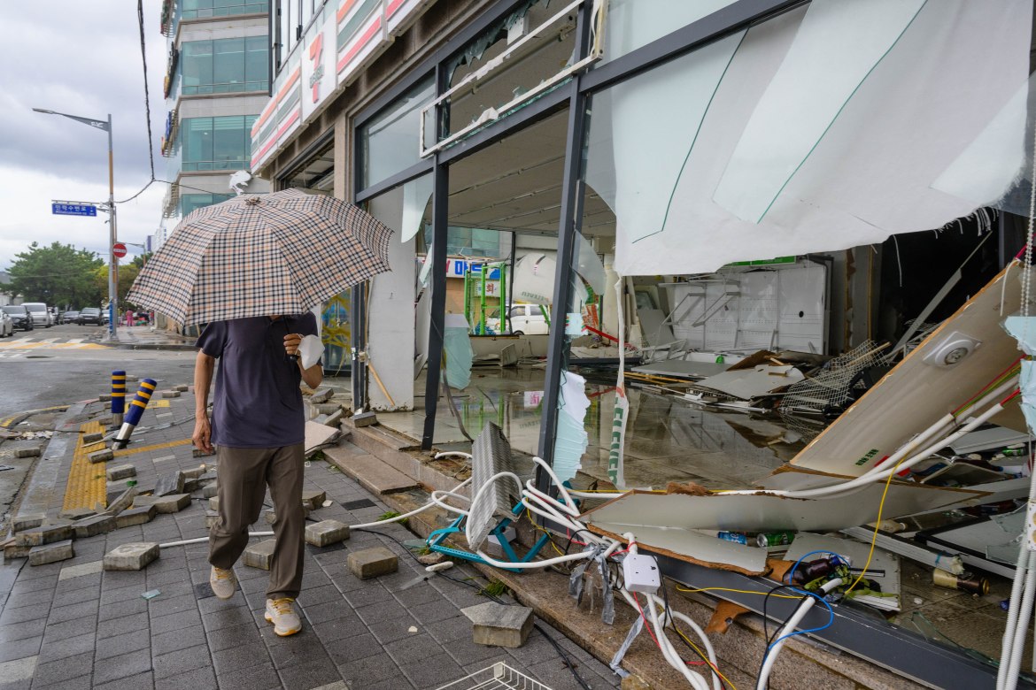 A pedestrian walks past a shop that was badly damaged
