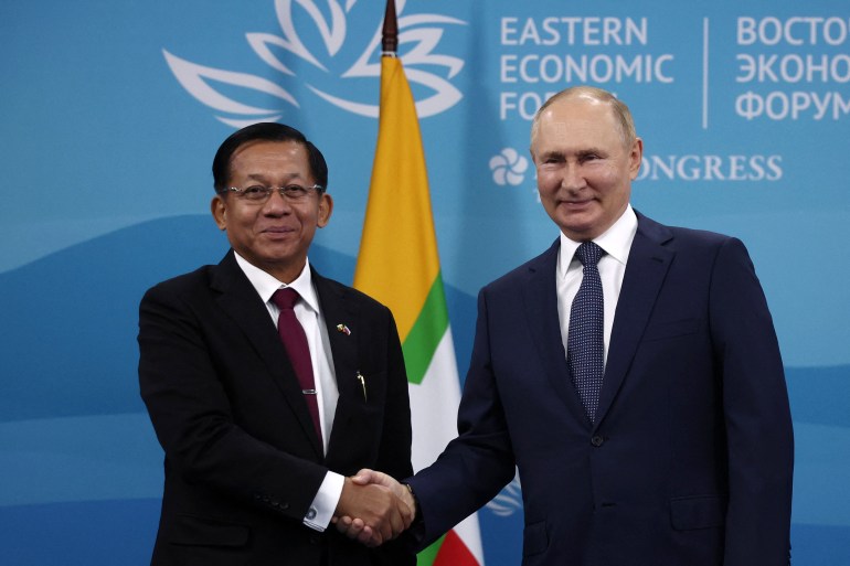 Min Aung Hlaing smiles as he shakes hands with Russian President Vladimir Putin