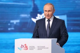 Putin speaking at a lectern.
