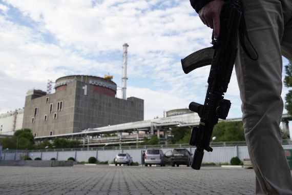 A security person, with a weapon by his side, stands in front of the Zaporizhzhia Nuclear Power Plant in Enerhodar, Zaporizhia Oblast.