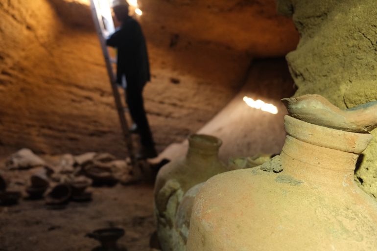 A handout picture provided by the Israel Antiquities Authority on Septembre 18, 2022, shows an archaeologist first entering a funerary cave discovered at the central Palmahim park area on the Mediterranean coast, containing untouched finds such as pottery vessels, dating back to the thirteenth century BCE during the rule of Egypt's Pharaoh Rameses II. - The cave was uncovered on a beach earlier in the week, when a mechanical digger working at the Palmahim national park hit its roof, with archaeologists using a ladder to descend into the spacious, man-made square cave. (Photo by Emil Aladjem / Israeli Antiquities Authority