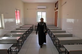 A woman is seen from behind walking in an empty classroom