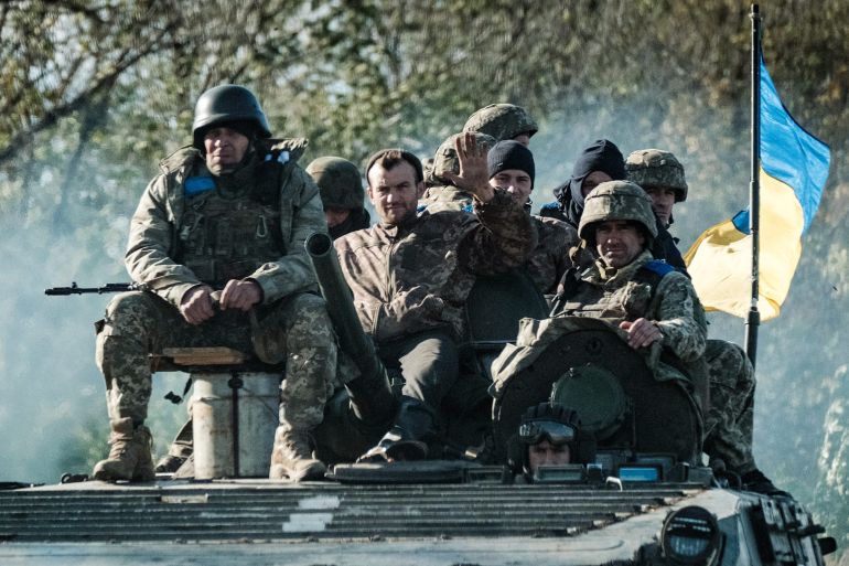 Ukrainian soldiers ride on an armoured vehicle in Novostepanivka, Kharkiv region, on September 19, 2022