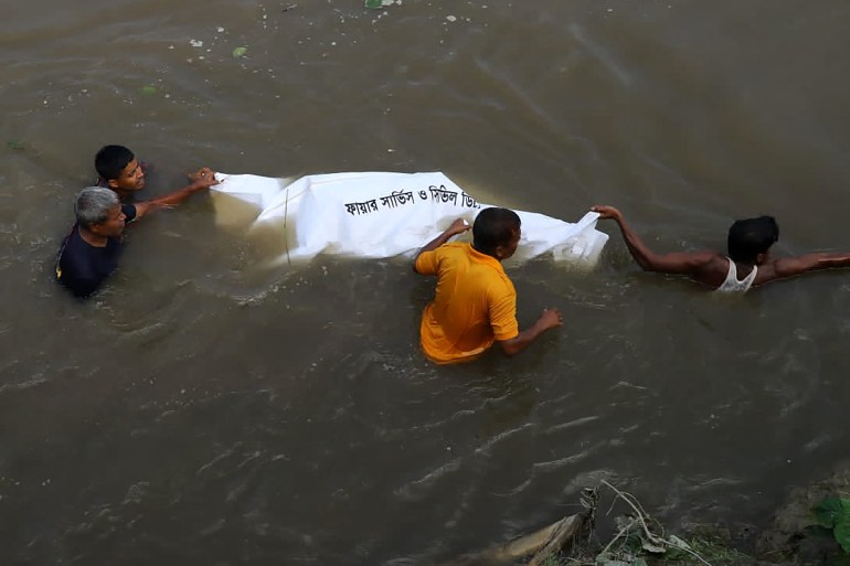 EDITORS NOTE: Graphic content / People pull the dead body of a victim who died after a boat capsized in river Karotoa near Boda town on September 26, 2022