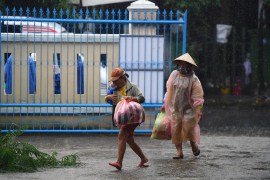 Two people carrying supplies outside a primary school being used as a shelter during Typhoon Noru in Hoi An in Vietnam&#39;s Quang Nam province on September 27, 2022 [Nhac Nguyen/AFP]