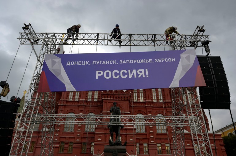 Workers fix a banner reading "Donetsk, Lugansk, Zaporizhzhia, Kherson - Russia!" in the Red Square in central Moscow.