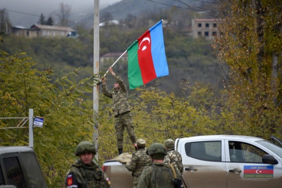 An Azerbaijani soldier fixes a national flag on a lamp post in the town of Lachin