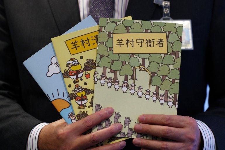 Three illustrated children's books featuring sheep characters on their covers held by senior superintendent Steve Li of the national security police.