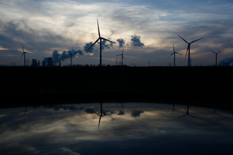 Wind generators and the Niederaussem coal power plant of RWE Power, one of Europe's biggest electricity and gas companies, are reflected in the roof of a car in Rheidt, north-west of Cologne October 11, 2012.