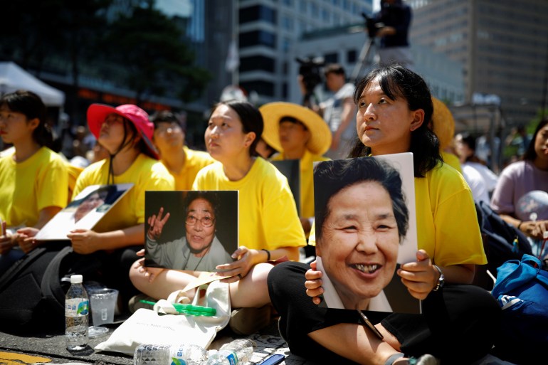 2018년 8월 15일 한국 서울에서 매주 열리는 반일 집회에서 학생들이 사망한 전 한국 "위안부"의 초상화를 들고 있다. 