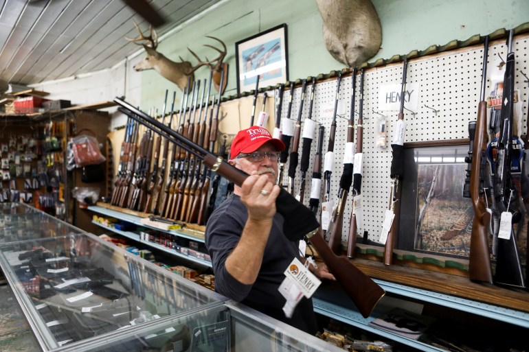 U.S. President Donald Trump supporter Richard Albrecht, a sales associate at Nordic Gun &amp; Pawn, displays a shotgun for a customer, in Wildwood, Florida, U.S. October 15, 2020.