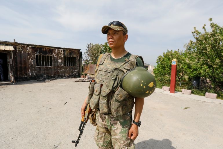 A Kyrgyz soldier stands with a weapon at the disputed border in 2021