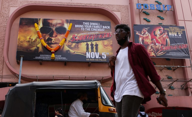 A man walks past posters of Bollywood film Sooryavanshi, outside a cinema in Mumbai, India, November 5, 2021.